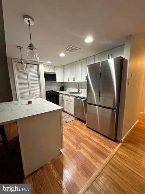 326 Queen Street, Unit 6 Philadelphia, PA 19147 - Photo 6 of 12 a kitchen with stainless steel appliances a refrigerator a sink dishwasher a stove and white cabinets with wooden floor
