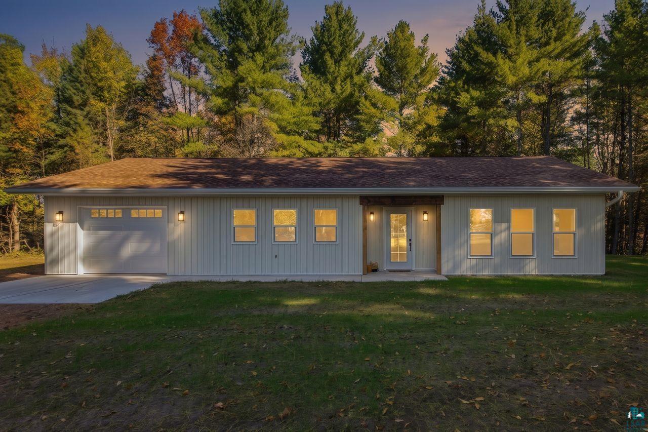 65352 Adler Road Marengo, WI 54855 - Photo 24 of 24 Single-story residence featuring white vertical siding, a brown shingle roof, attached garage with a concrete driveway, and a covered entry with dual glass panel doors