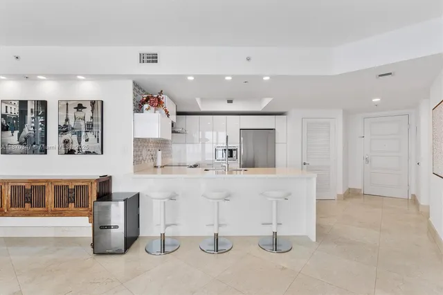 a large white kitchen with a lot of cabinets stainless steel appliances and a large window