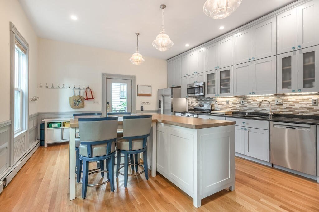 45 M Street Boston, MA 02127 - Photo 12 of 42 a kitchen with granite countertop a stove a sink a dining table and chairs with wooden floor