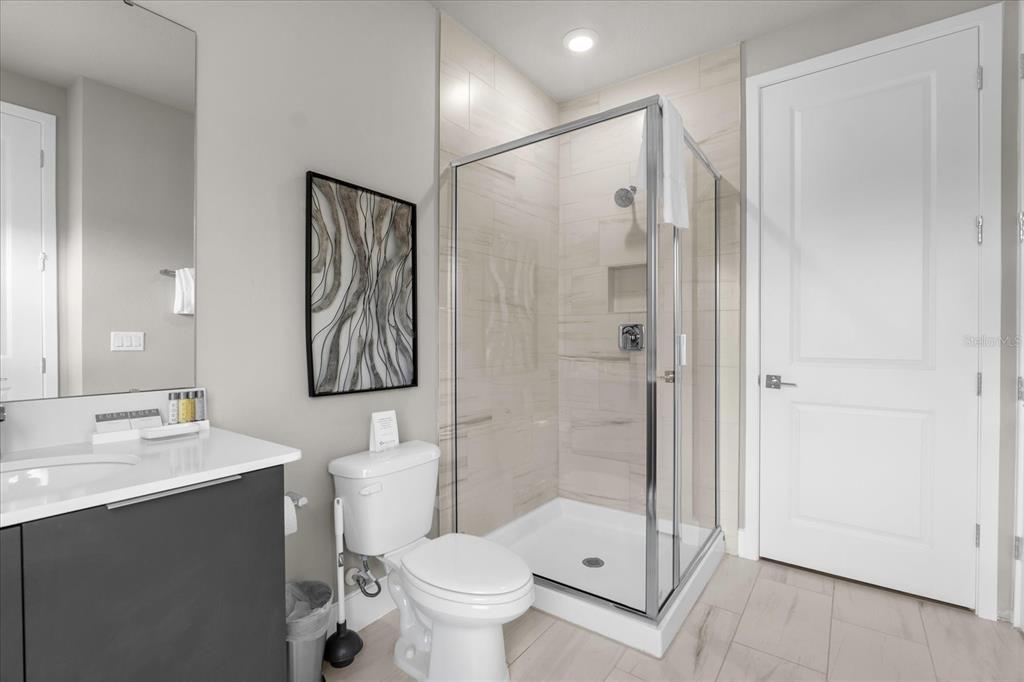 7770 Sandy Ridge Drive, Unit 227 Reunion, FL 34747 - Photo 28 of 33 a bathroom with a shower sink vanity mirror and toilet