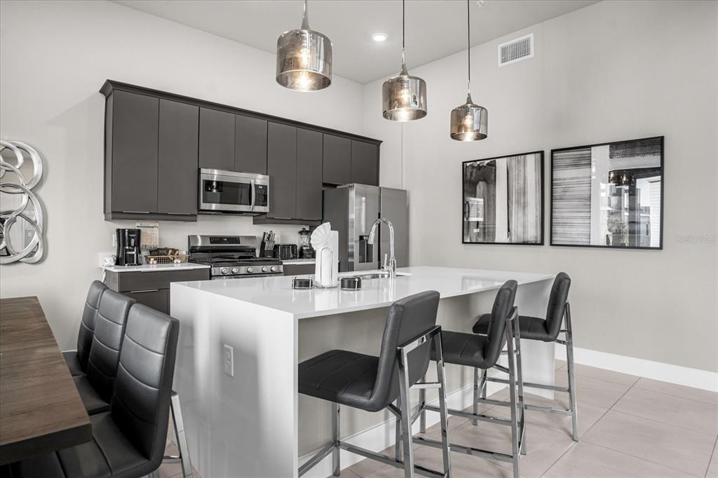 7770 Sandy Ridge Drive, Unit 227 Reunion, FL 34747 - Photo 7 of 33 a kitchen with stainless steel appliances a table chairs refrigerator and microwave