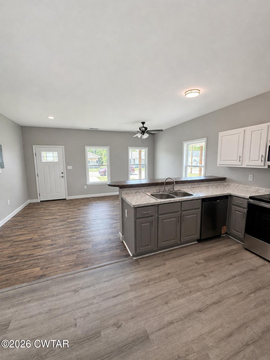 103 Dempster Street Jackson, TN 38301 - Photo 6 of 18 a large kitchen with kitchen island a sink dishwasher a stove and white cabinets with wooden floor