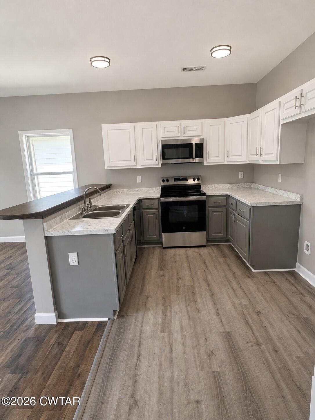 103 Dempster Street Jackson, TN 38301 - Photo 10 of 18 a large kitchen with stainless steel appliances granite countertop a stove a sink dishwasher and a refrigerator with wooden floor