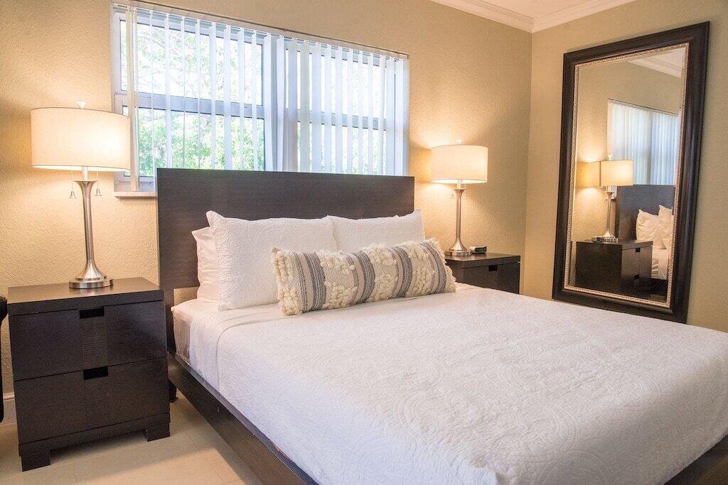 Undisclosed Address Pompano Beach, FL 33062 - Photo 14 of 16 a large bed sitting in a bedroom next to a window and lamp