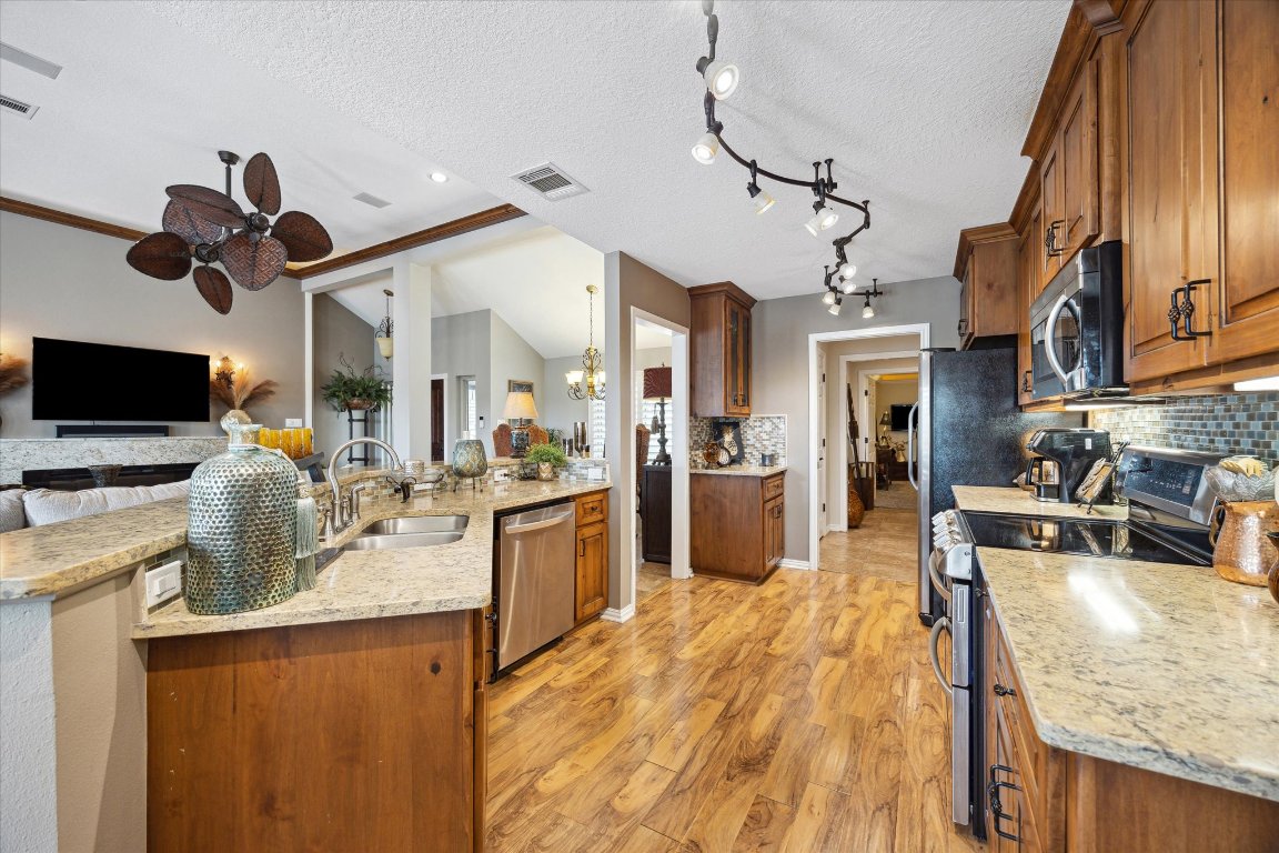 515 Wesley Ridge Drive Spicewood, TX 78669 - Photo 33 of 36 a kitchen with stainless steel appliances granite countertop sink stove top oven and cabinets