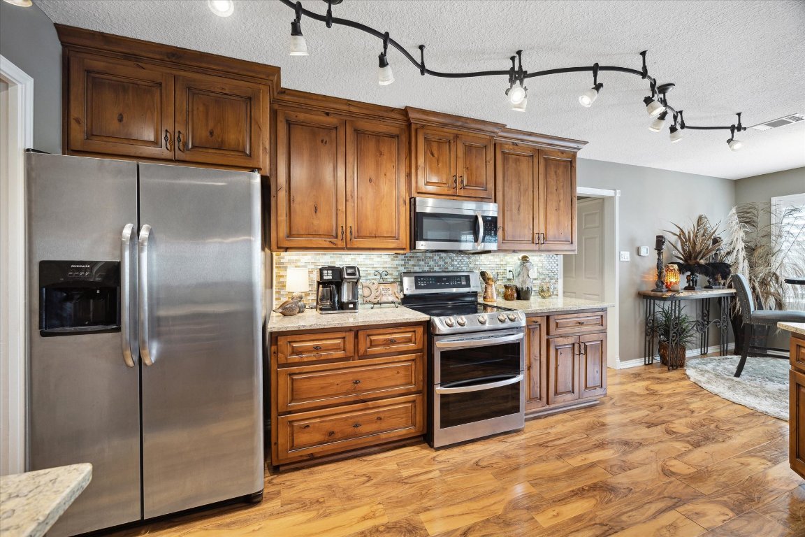 515 Wesley Ridge Drive Spicewood, TX 78669 - Photo 12 of 36 a kitchen with stainless steel appliances granite countertop a refrigerator a stove and a sink with wooden floor