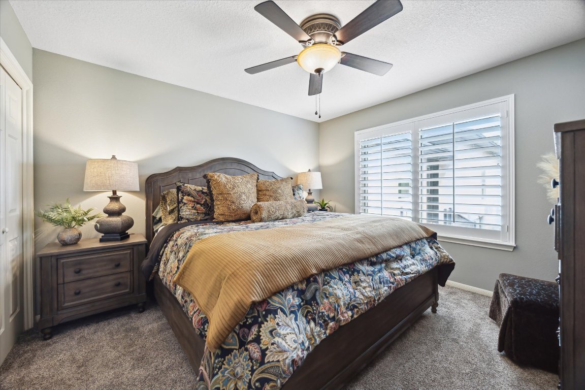 515 Wesley Ridge Drive Spicewood, TX 78669 - Photo 24 of 36 a bedroom with a bed and a chandelier