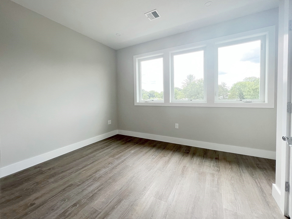 80 Bridge Street, Unit 303 Dedham, MA 02026 - Photo 12 of 18 an empty room with wooden floor and windows