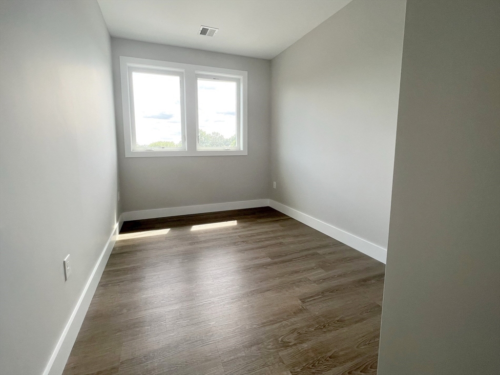 80 Bridge Street, Unit 303 Dedham, MA 02026 - Photo 15 of 18 an empty room with wooden floor and windows