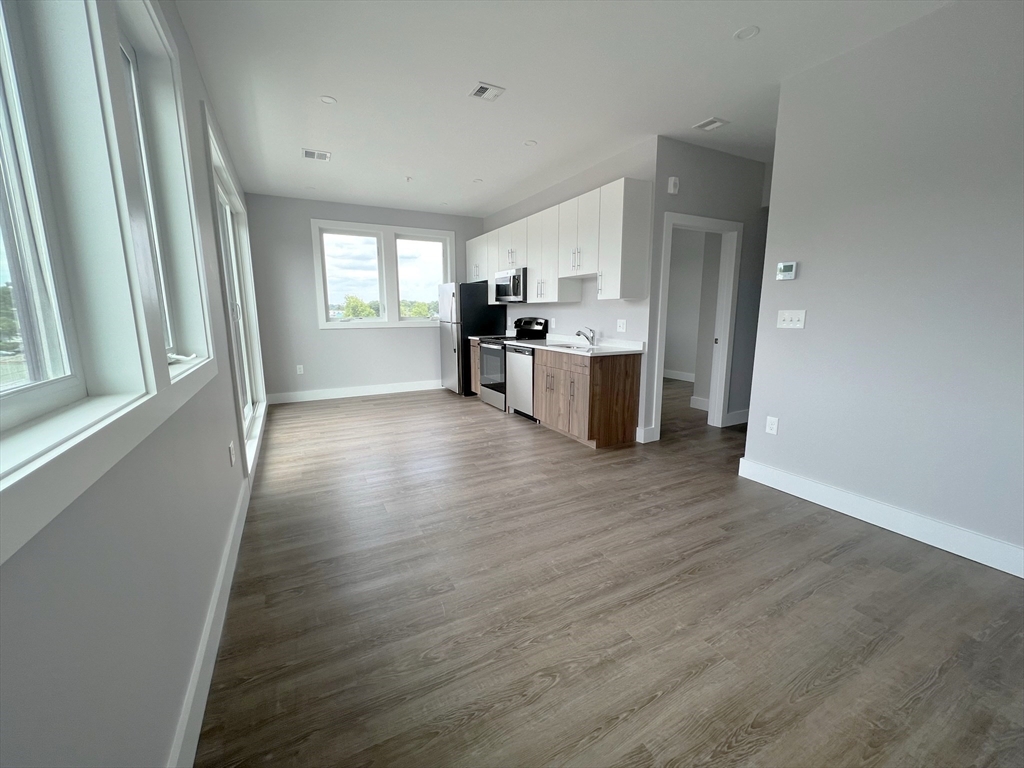 80 Bridge Street, Unit 303 Dedham, MA 02026 - Photo 7 of 18 a view of a kitchen with wooden floor and electronic appliances