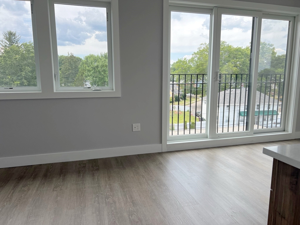 80 Bridge Street, Unit 303 Dedham, MA 02026 - Photo 8 of 18 a view of an empty room with wooden floor and a window