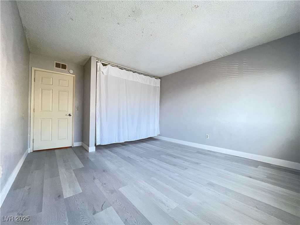 1709 Fairfield Avenue, Unit G Las Vegas, NV 89102 - Photo 13 of 15 Unfurnished bedroom featuring light wood-type flooring and a textured ceiling