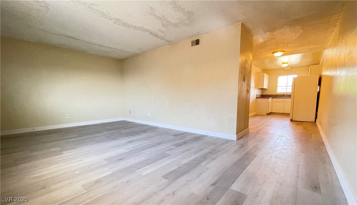 1709 Fairfield Avenue, Unit G Las Vegas, NV 89102 - Photo 5 of 15 Empty room featuring a textured ceiling and light wood-type flooring