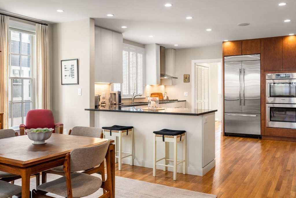 16 York Terrace Brookline, MA 02446 - Photo 11 of 42 a kitchen with stainless steel appliances granite countertop a table chairs and a refrigerator