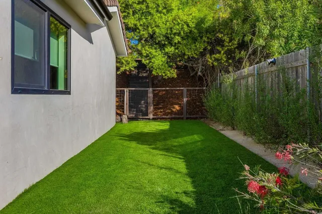 a view of a backyard with potted plants and large trees