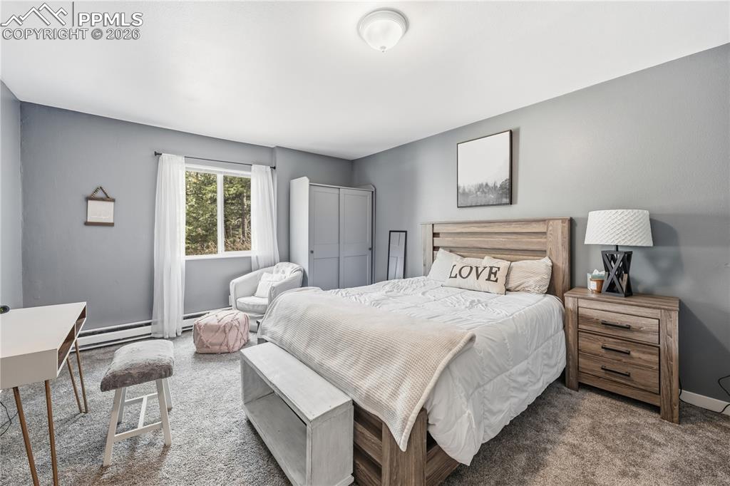 5130 Neeper Valley Road Manitou Springs, CO 80829 - Photo 29 of 38 a bedroom with a bed a chandelier and a dresser