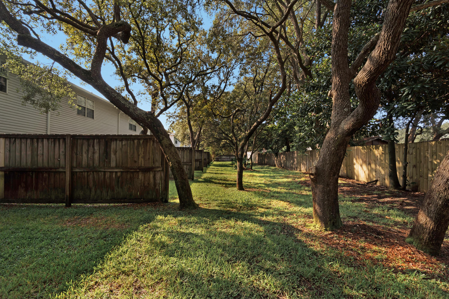 212 Tooke Street, Unit A Fort Walton Beach, FL 32547 - Photo 24 of 26 a view of a backyard with large trees and wooden fence