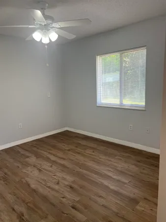a view of an empty room with wooden floor and a window