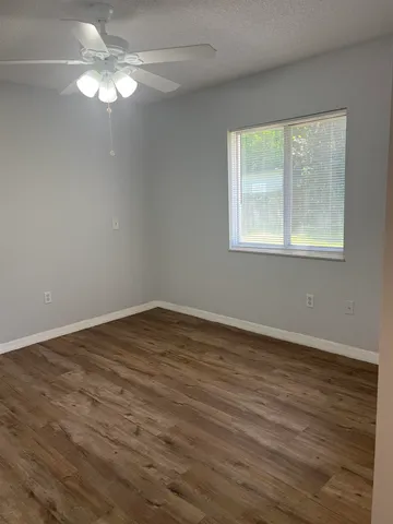 a view of an empty room with wooden floor and a window