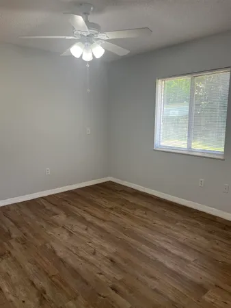 a view of an empty room with wooden floor and a window