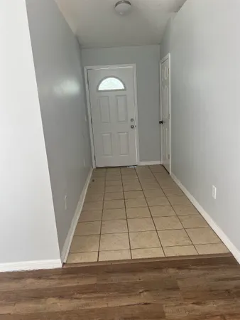a view of an empty room with wooden floor and a ceiling fan