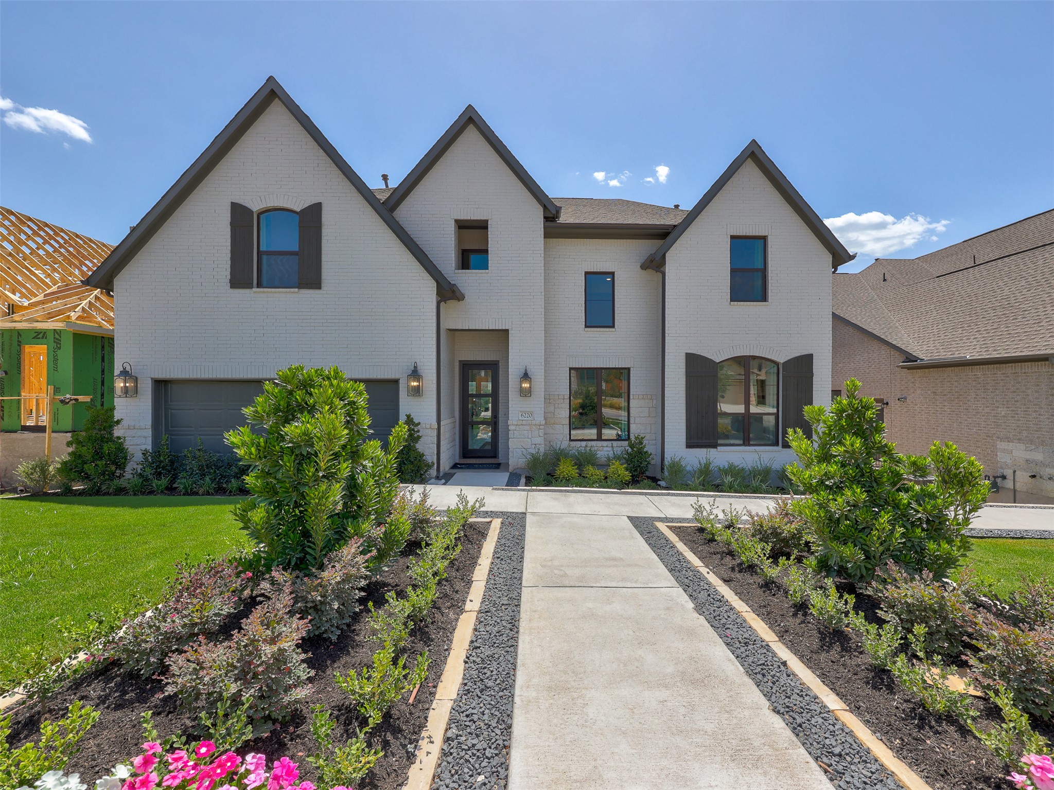 6220 Bower Well Road Austin, TX 78738 - Photo 1 of 28 A grand white brick facade with dark shutters and well-manicured landscaping welcomes visitors.