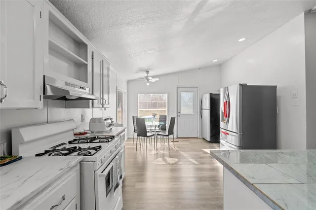 a kitchen with stainless steel appliances granite countertop a stove refrigerator and cabinets