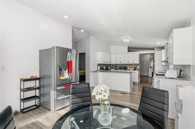 a living room with stainless steel appliances furniture a rug and a kitchen view