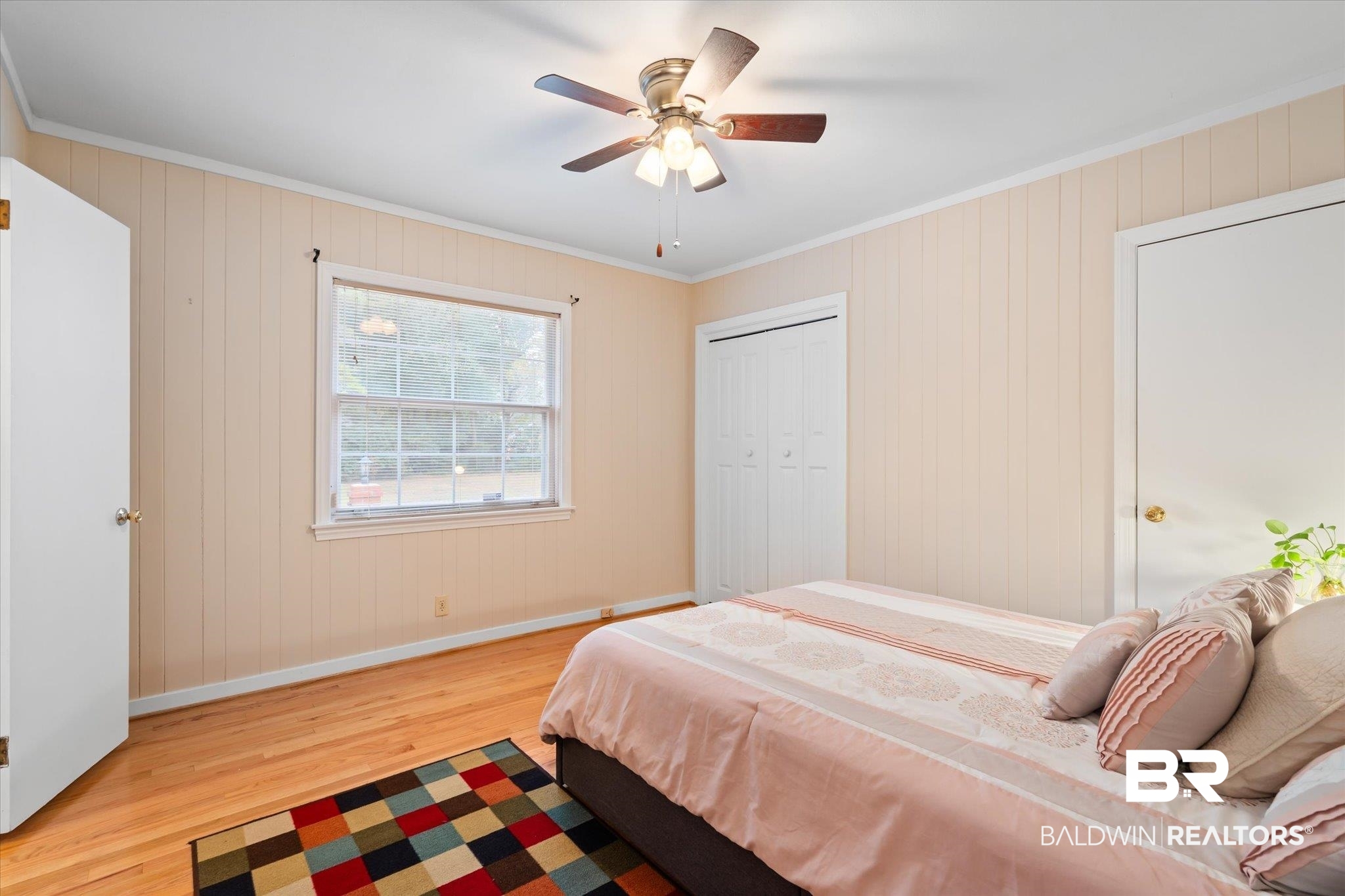 162 Bit And Spur Terrace Mobile, AL 36608 - Photo 11 of 29 Bedroom featuring a closet, wooden walls, ornamental molding, light hardwood / wood-style floors, and ceiling fan