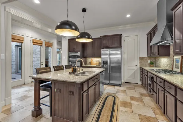 a kitchen with stainless steel appliances granite countertop a sink a stove and a refrigerator