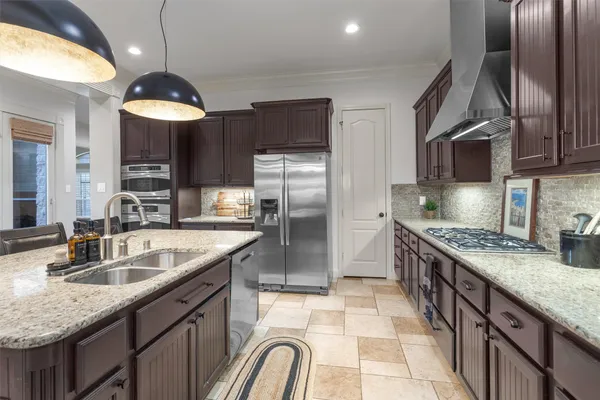 a kitchen with stainless steel appliances granite countertop a sink a stove and a refrigerator