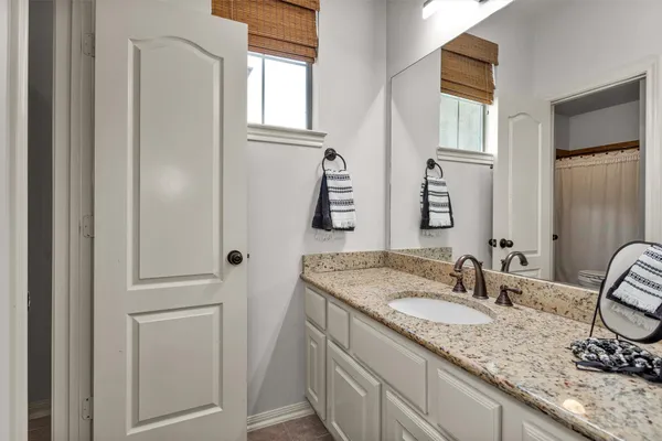 a bathroom with a granite countertop sink and a mirror