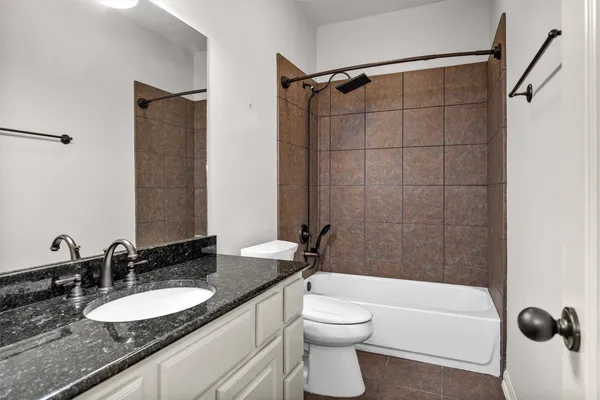 a bathroom with a granite countertop sink mirror toilet and bathtub