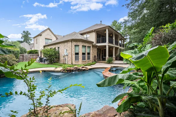 a front view of a house with swimming pool and porch with furniture