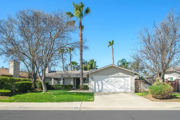 a front view of a house with a garden and trees