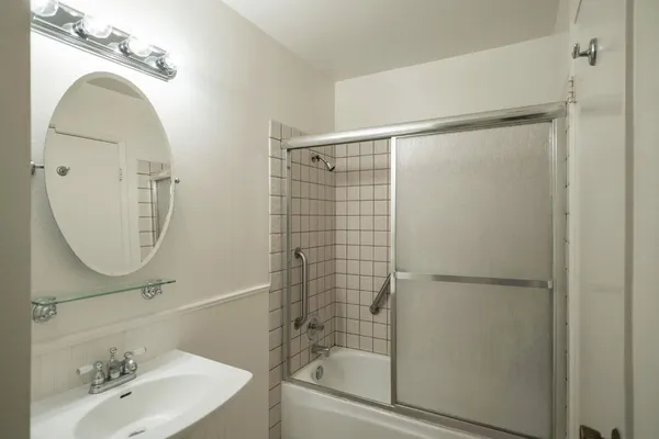 a bathroom with a shower a mirror and a sink