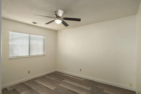 an empty room with a window and a fan