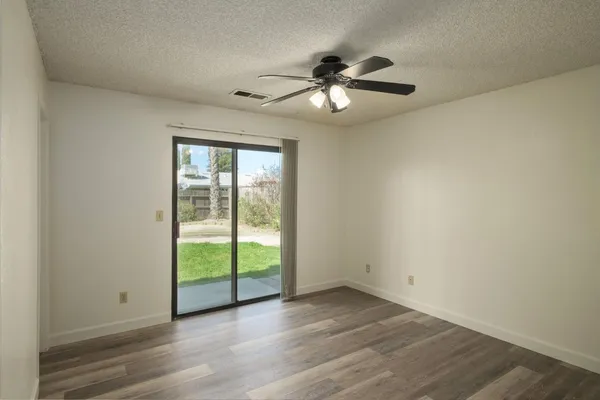 an empty room with wooden floor fan and windows