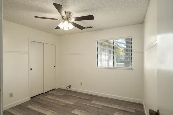 a view of an empty room with wooden floor and a window