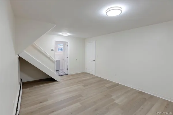 a view of an empty room with wooden floor and stairs