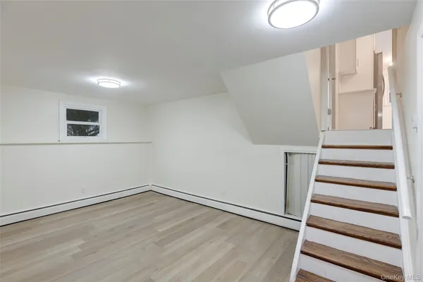 a view of an empty room with wooden floor and white walls