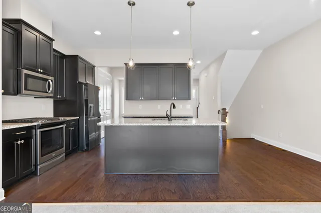 a large kitchen with stainless steel appliances a large counter top a stove a refrigerator and a sink