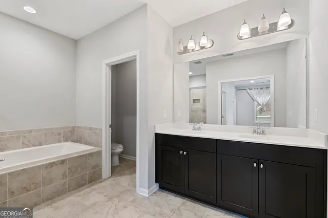 a bathroom with a tub a double vanity sink and a mirror