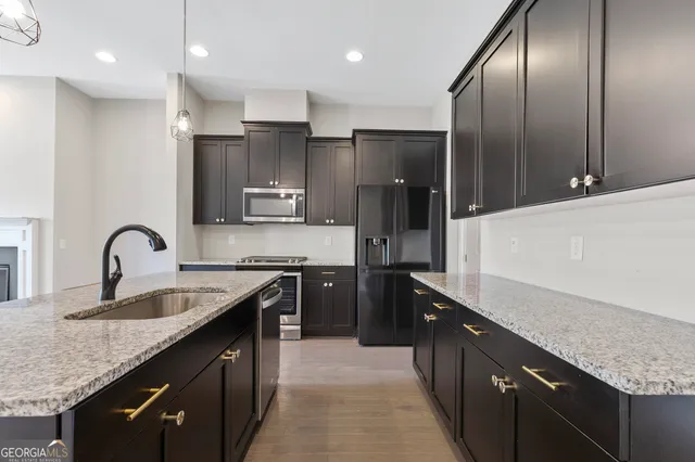 a kitchen with granite countertop stainless steel appliances a sink stove top oven and refrigerator