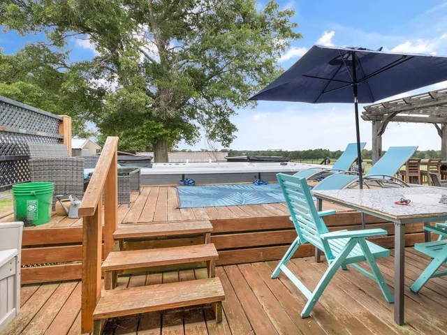a view of a patio with table and chairs under an umbrella with wooden floor