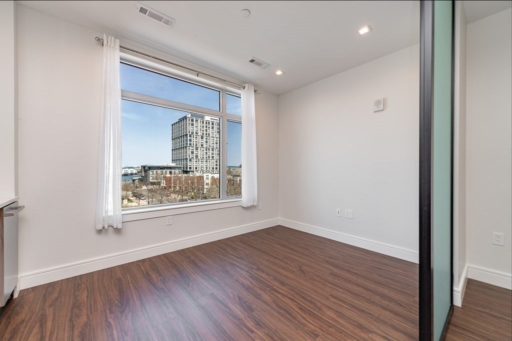 99 Sumner Street, Unit 413 Boston, MA 02128 - Photo 2 of 17 a view of an empty room with wooden floor and a window