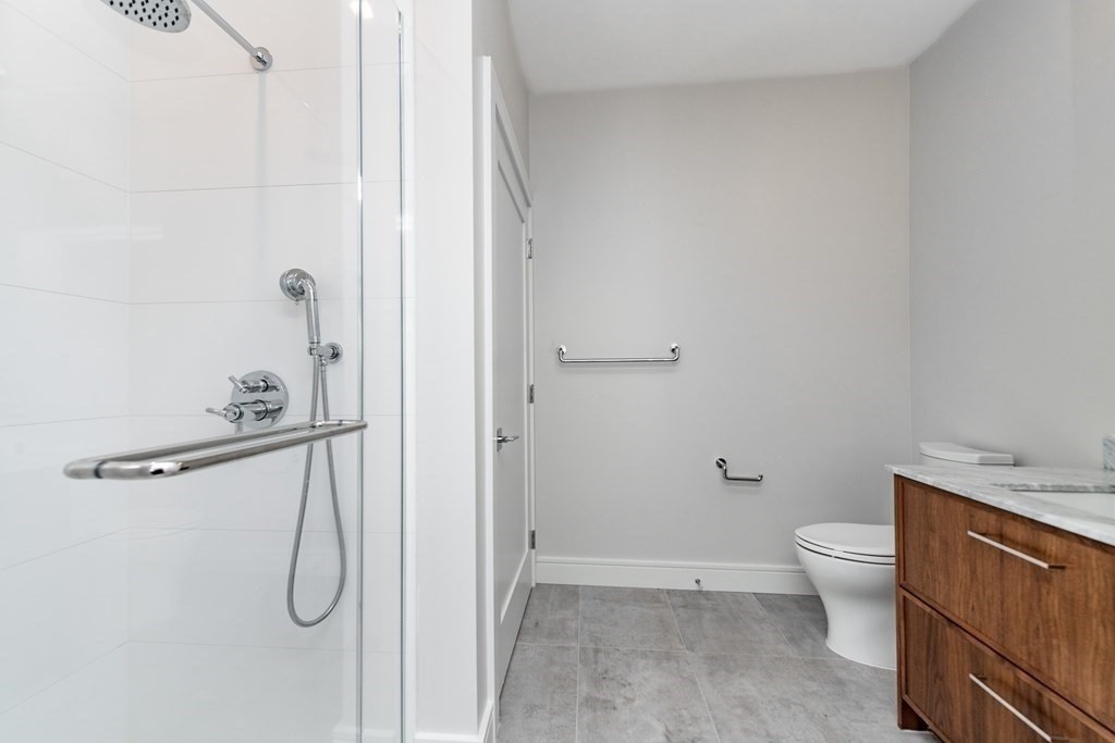 99 Sumner Street, Unit 413 Boston, MA 02128 - Photo 5 of 17 a bathroom with a granite countertop shower and a toilet