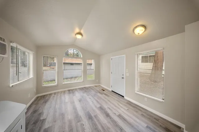 an empty room with wooden floor cabinet and windows