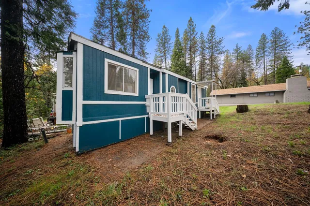 a view of a house with backyard wooden deck and a tree